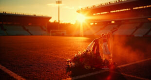 Memorial flowers and football scarves placed at empty stadium gates bathed in golden sunset light
