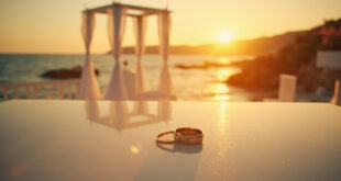 Wedding rings on white marble surface by empty altar along Mediterranean coastline at golden hour sunset