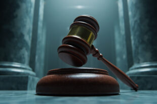 Wooden judge's gavel resting on sound block in formal courthouse setting with marble columns