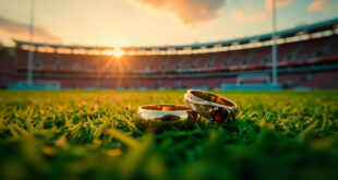 Two golden wedding rings sitting on green artificial turf of empty football field with stadium seats visible