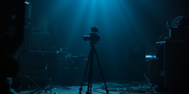 Dark streaming room with powered-off camera equipment and monitors, cables scattered across desk.
