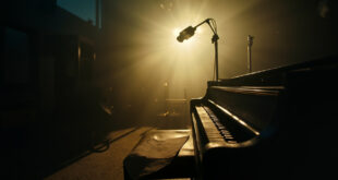 Unopened sheet music rests on a piano bench in an abandoned recording studio at twilight, with a silent microphone stand nearby.
