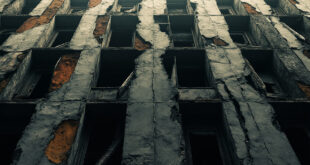 Weathered concrete apartment building with broken windows and cracked facade showing urban decay