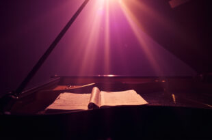 Abandoned grand piano with closed lid and unopened sheet music in a quiet music studio at twilight bathed in purple and gold light