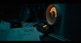 Stack of energy bills beside calculator and heating thermostat in moody lighting with warm amber and cold blue tones