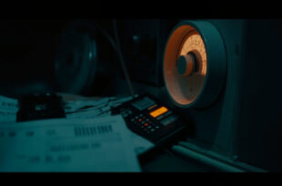Stack of energy bills beside calculator and heating thermostat in moody lighting with warm amber and cold blue tones