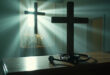 Empty medical consultation room with stethoscope beside wooden cross on desk, blending hospital and chapel elements
