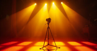 Vintage television camera facing empty stage with spotlight on abandoned microphone in 1950s TV studio