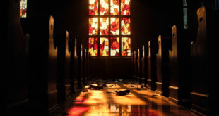 Broken stained glass church window with colorful fragments scattered on wooden floor below