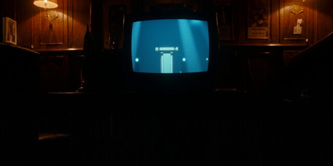 Television screen showing quiz show set mounted on pub wall with empty tables and chairs visible