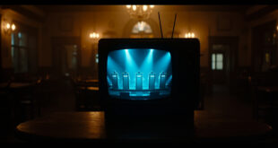 Television screen in darkened pub showing quiz show set with contestant podiums and game show lighting