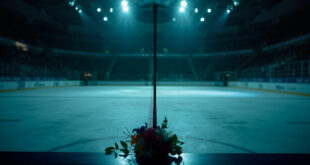 Hockey stick leaning against arena boards with memorial flowers and soft arena lighting