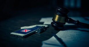 Wooden gavel beside smartphone displaying blocked social media icons on courtroom desk