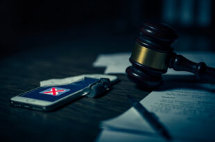 Wooden gavel beside smartphone displaying blocked social media icons on courtroom desk