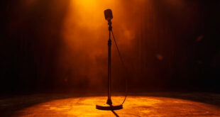Vintage microphone standing alone on dimly lit Grand Ole Opry wooden stage with burgundy curtains and amber spotlight