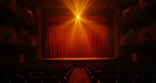 Empty Las Vegas theater stage with postponed show announcement, dimmed lights and vacant seats in amber and burgundy hues