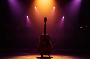 Acoustic guitar on stand under amber spotlight on empty concert stage with purple shadows