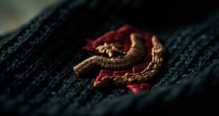 Close-up of red hammer and sickle symbol with star embroidered on black knitted fabric