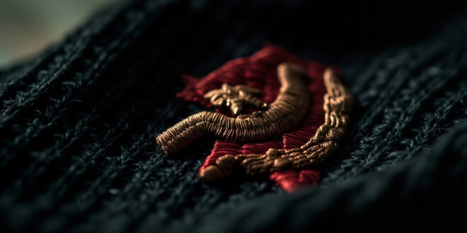 Close-up of red hammer and sickle symbol with star embroidered on black knitted fabric