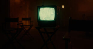 Vintage television set with glowing amber screen displaying static in darkened room