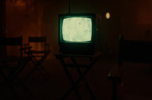 Vintage television set with glowing amber screen displaying static in darkened room