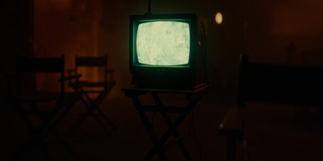 Vintage television set with glowing amber screen displaying static in darkened room