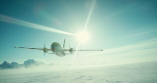Solitary aircraft flying over snowy Alaskan wilderness approaching distant airport under vast arctic blue sky