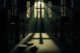 Empty wooden church pews in dim cathedral with stained glass windows casting colored light across the floor.