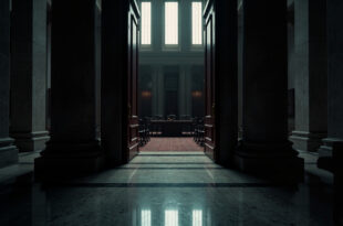 Closed ornate wooden doors of government building with brass handles and marble surroundings