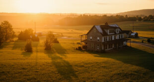 Rustic farmhouse surrounded by rolling green pastures and wooden fences in golden afternoon light