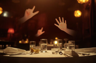 Empty restaurant table with place settings in warm lighting, with space above showing sign language gestures