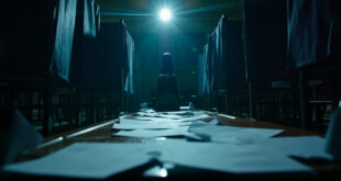 Empty ballot boxes and unmarked papers on counting table in vacant parliamentary chamber at dusk, with closed voting booths
