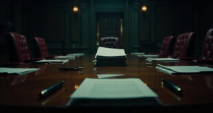 Official documents and fountain pens arranged on dark wooden conference table in formal government setting