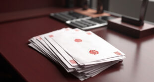 Stack of official documents with red seals next to calculator on wooden government desk