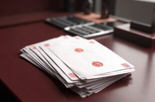 Stack of official documents with red seals next to calculator on wooden government desk
