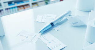 Medical injection pen device on pharmacy counter with price tags and pharmaceutical documentation.