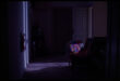 Dark hallway with closed door, colorful fabric draped nearby, scattered personal belongings on floor.