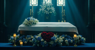 Oak casket on church altar surrounded by white and blue flower wreaths and heart-shaped memorial arrangement