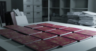 Stack of international passports arranged on government desk with official documents and data charts nearby