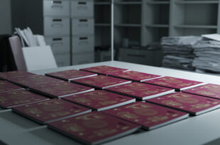 Stack of international passports arranged on government desk with official documents and data charts nearby
