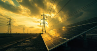 High-voltage electrical transmission towers and power lines stretching across industrial landscape with solar installations