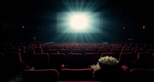 Empty movie theater with red seats facing illuminated screen, popcorn bowl on armrest.