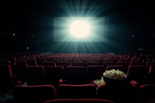 Empty movie theater with red seats facing illuminated screen, popcorn bowl on armrest.