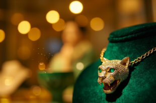 Cartier panther necklace with emerald eye displayed on luxury velvet stand in elegant jewelry boutique display case