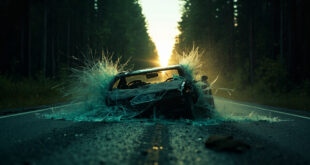 Abandoned car with shattered windshield sits on an empty forest road at dusk following wildlife collision