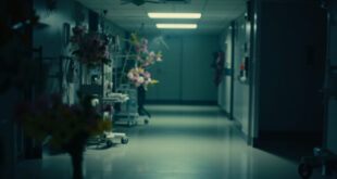 Hospital intensive care room with medical equipment and pink and yellow flowers on bedside table