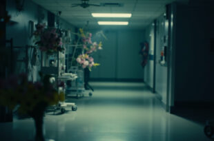 Hospital intensive care room with medical equipment and pink and yellow flowers on bedside table