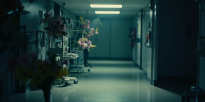 Hospital intensive care room with medical equipment and pink and yellow flowers on bedside table