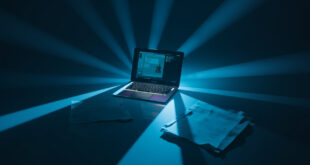 Dark laptop screen with chat interface glowing in empty room with legal papers on desk