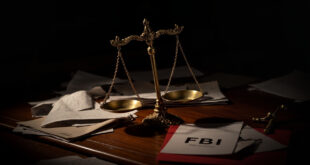 Tilted scales of justice on dark desk surrounded by scattered legal documents and government folders in dramatic lighting